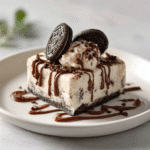 No‑Bake Oreo Ice Cream Dessert: 7-Minute Irresistible Delight 9 No-Bake Oreo Ice Cream Dessert slice served with chocolate drizzle and mini Oreo on a white plate