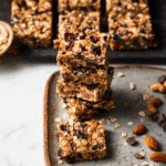 Peanut Butter Trail Mix Bars: 7 Reasons to Love This Snack 9 Stack of Peanut Butter Trail Mix Bars on a plate with scattered ingredients.