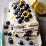 Blueberry Lemon Icebox Cake: 7‑Ingredient Summer Delight 9 Slice of Blueberry Lemon Icebox Cake on a plate with lemon zest and blueberries
