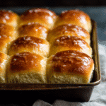 Freshly baked honey butter rolls brushed with warm honey butter in a baking dish