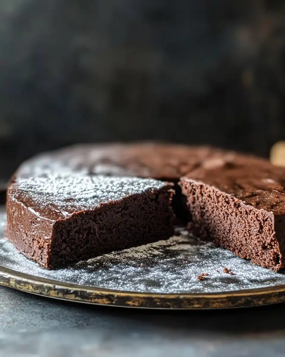 Delicious Flourless Chocolate Cake topped with cocoa powder and berries.
